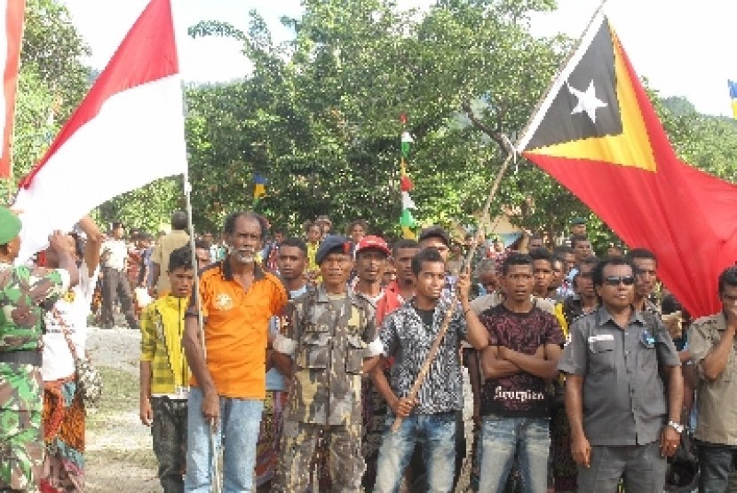 People from Indonesia and Timor Leste hoist flags of both countries after the closing ceremony of military's personnel community service in Mutis distric (Indonesia) and Oecusse district (Timor Leste). Timor Leste plans to open border trade zone in Oecusse