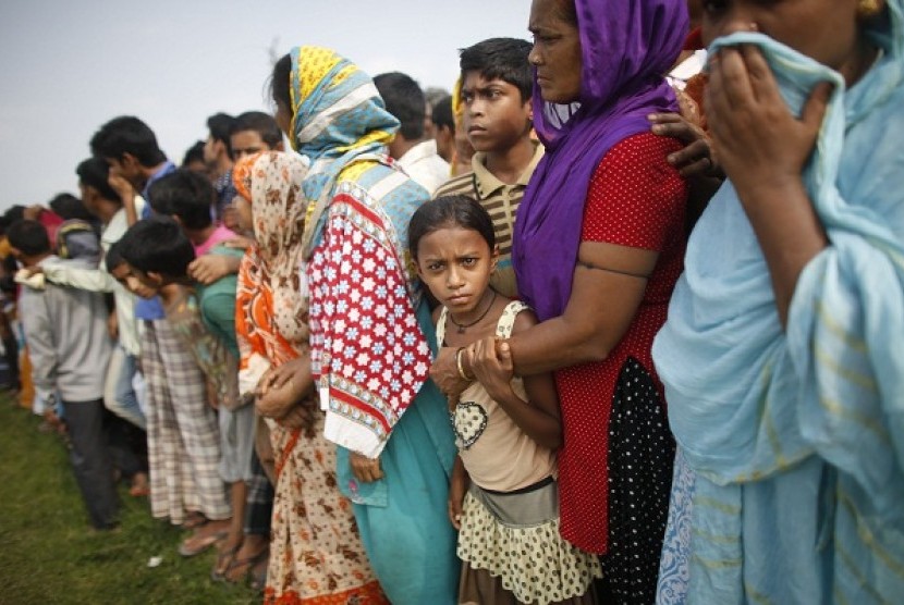 People gather in front of mass graves during the burial of unidentified garment workers, who died in the collapse of the Rana Plaza building in Savar, in Dhaka May 1, 2013. 