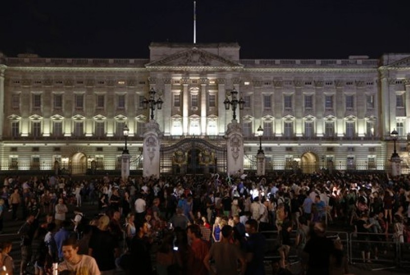People gather outside a floodlit Buckingham Palace in London to mark the birth of a baby boy to Prince William and Kate, Duchess of Cambridge, Monday, July 22, 2013. 