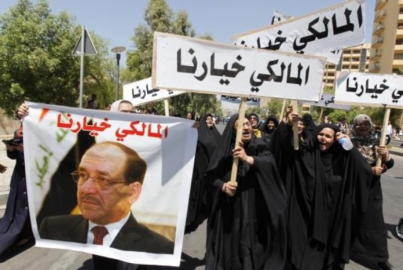 People hold a portrait of Nuri al-Maliki and signs as they gather in support of him in Baghdad August 13, 2014.