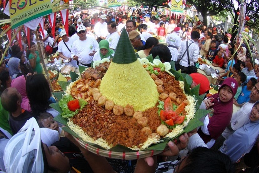 People struggle to seize a cone-shaped rice or locally called Nasi Tumpeng in a tumpeng festival Solo (illustration)  