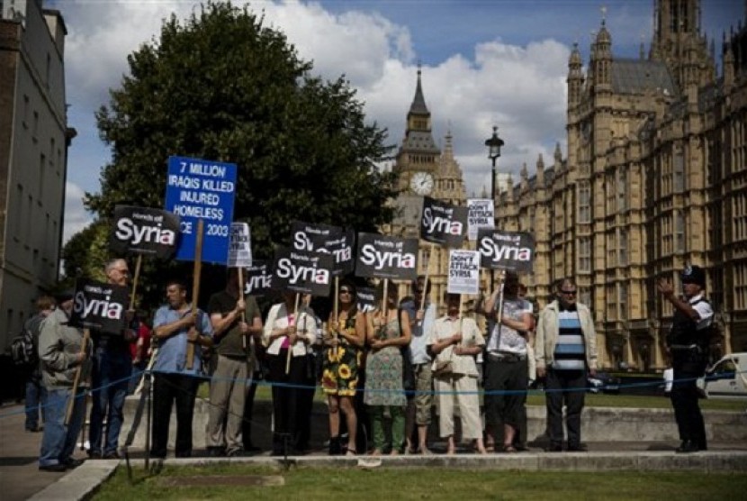 People take part in a protest calling for no military attack on Syria outside the Houses of Parliament, in London, organized by the Stop the War coalition and timed to coincide with a debate and vote by politicians, Thursday, Aug. 29, 2013. 