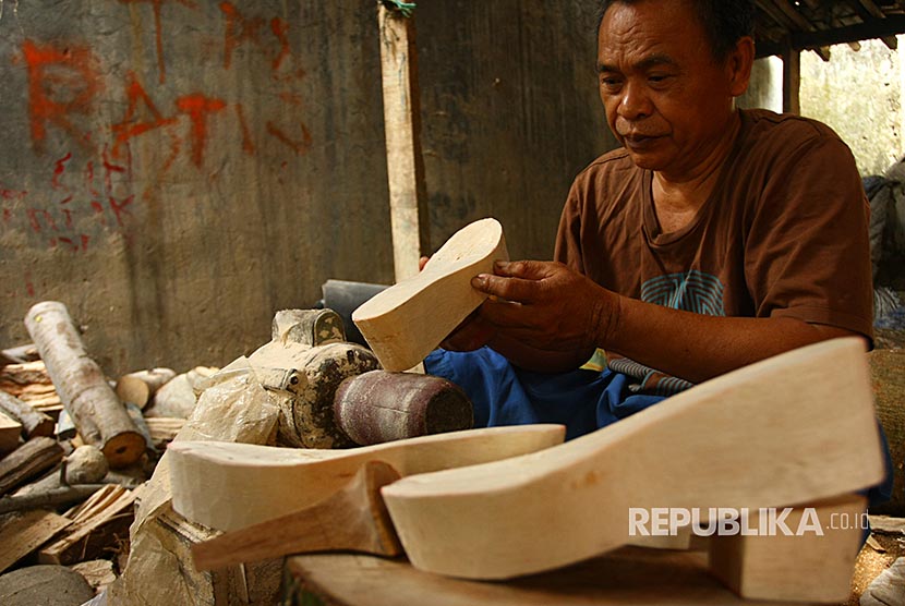 Perajin bahan sepatu, Mukhtar (65), menghaluskan bahan baku pembuatan sandal wedges di Bintaro, Tangerang Selatan, Banten, Rabu (8/11). Kerajinan berbahan baku dari kayu sengon dan dibandrol dengan harga Rp16 ribu per pasang tersebut dibuat untuk memenuhi permintaan UMKM perajin sepatu wedges yang ada di Tangerang, Bogor, dan Bekasi. 