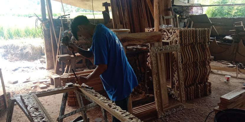 Salah pegawai dari perajin kayu Bali, Wayan Sudarsana sedang mengerjakan salah satu ukiran. 