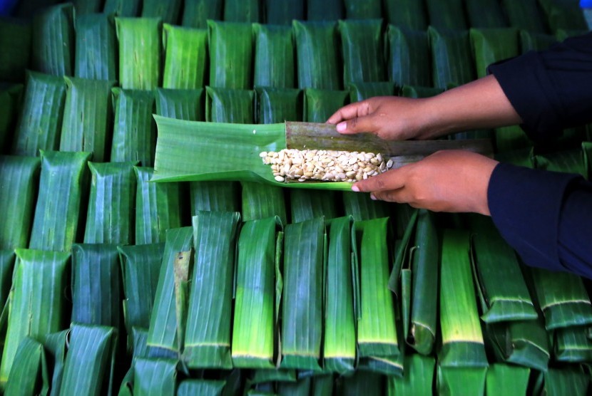 Perajin menyelesaikan pembuatan tempe menggunakan daun pisang.