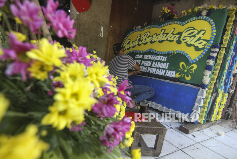 Perajin menyelesaikan produksi karangan bunga duka cita di Kawasan Jalan Raya Pondok Gede, Jakarta Timur, Ahad (18/7/2021). Perajin mengatakan permintaan karangan bunga duka cita tersebut mengalami peningkatan yang sebelumnya produksi 10 karangan bunga per hari menjadi 30 karangan bunga per hari.