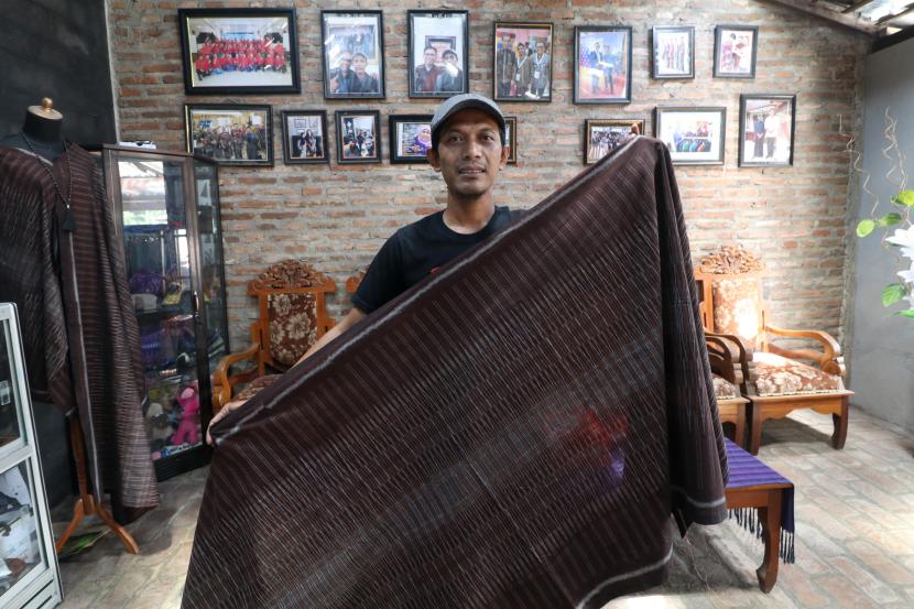 Perajin tenun ikat Erwin Wahyu Nugroho memperlihatkan desain kain tenun karyanya yang telah dipakai oleh Presiden Joko Widodo, di kampung tenun Bandar Kidul, Kota Kediri, Jawa Timur, Senin (31/10/2022). Menurut Erwin, setelah kain tenun ikat buatannya dipakai Presiden Joko Widodo pada pembukaan Trade Expo Indonesia (TEI) ke-37 dirinya mendapatkan banyak pesanan kain tenun dengan desain serupa dan bersiap memberikan pelatihan desain kepada perajin lainnya guna memajukan perekonomian Kampung Tenun Bandar Kidul. 