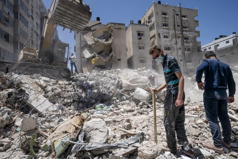 Peralatan konstruksi berat digunakan untuk menyaring puing-puing untuk menemukan barang-barang berharga sebelum diangkut dari lokasi bangunan yang hancur dalam serangan udara sebelum gencatan senjata yang menghentikan perang 11 hari antara penguasa Hamas di Gaza dan Israel, Kamis, Mei. 27, 2021, di Kota Gaza.