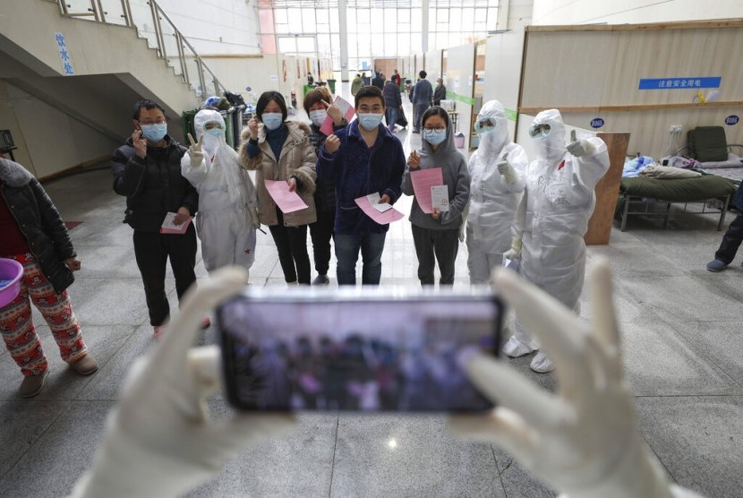 Perawat berpose dengan pasien yang dinyatakan sembuh dari virus corona di Tazihu Gymnasium, Wuhan, China, Jumat (21/2). Berdasarkan data resmi Organisasi Kesehatan Dunia (WHO), terdapat 599 kasus baru sepanjang Sabtu (22/2) yang dilaporkan melambat dibandingkan hari-hari sebelumnya.