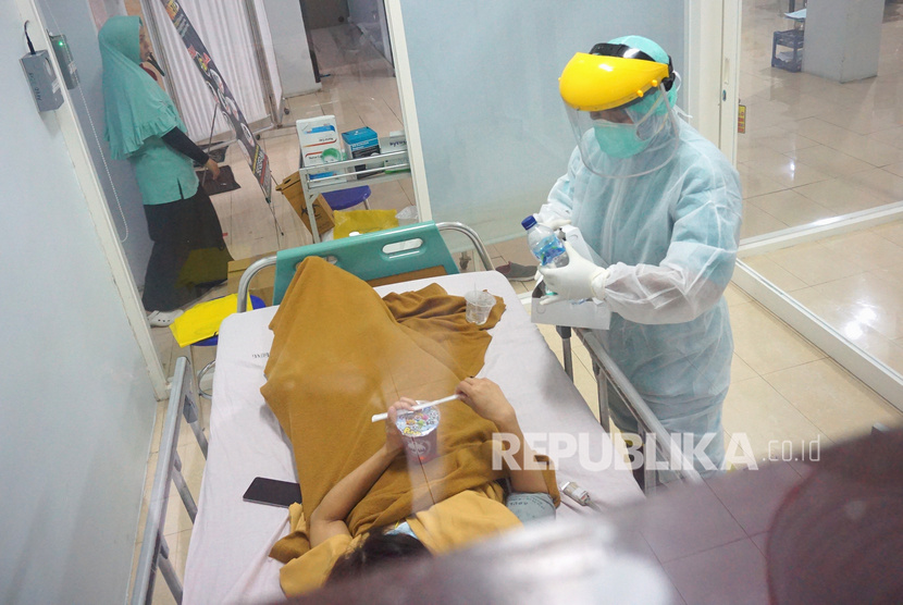 Perawat dengan mengenakan pakaian APD (Alat Pelindung Diri) berupa baju Hazmat (Hazardous Material) melayani pasien.