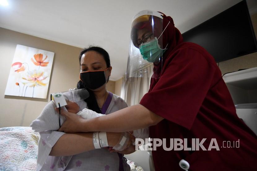 Perawat mengantarkan bayi yang memakai pelindung muka atau face shield di RS Ibu dan Anak Asih, Jakarta, Jumat (17/4/2020). RSIA Asih memberikan perlindungan dini berupa pelindung muka atau 