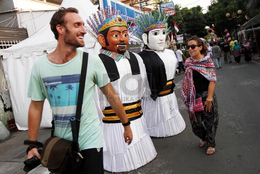 Turis asing melintasi ondel-ondel saat Festival Jaksa, Jakarta, Jumat (22/8). (Republika/ Yasin Habibi)