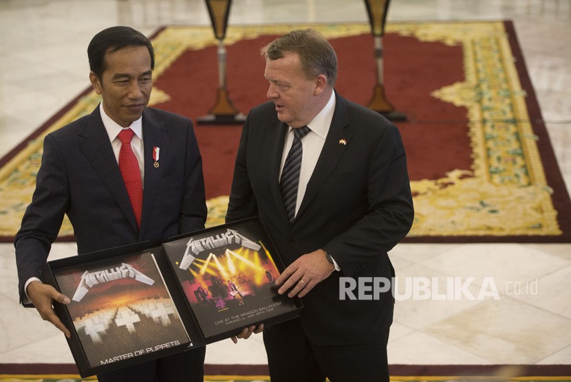 Perdana Menteri Denmark Lars Lokke Rasmussen (kanan) memberi Presiden Joko Widodo cendera mata berupa piringan hitam band Metallica usai pernyataan bersama kedua negara dalam kunjungan kerja perdana menteri Denmark di Istana Bogor, Bogor, Jawa Barat, Selasa (28/11).