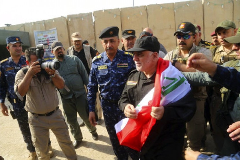 Perdana Menteri Irak Haider al-Abadi (tengah) memegang bendera nasional saat tiba di Mosul, Irak, Ahad, 9 Juli 2017. 
