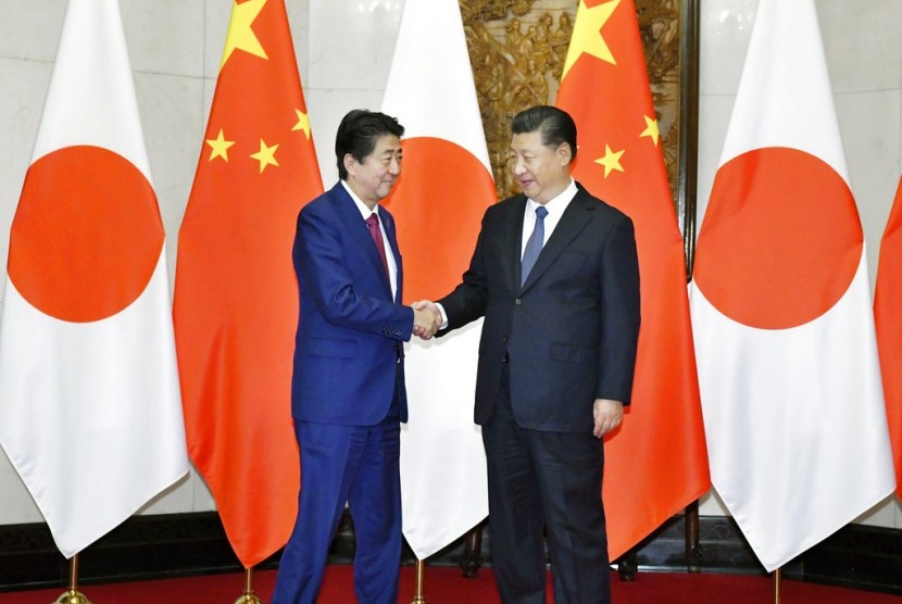 Perdana Menteri Jepang Shinzo Abe (kiri) berjabat tangan dengan Presiden Cina Xi Jinping di Diaoyutai State Guesthouse di Beijing, Cina, Jumat (26/10).