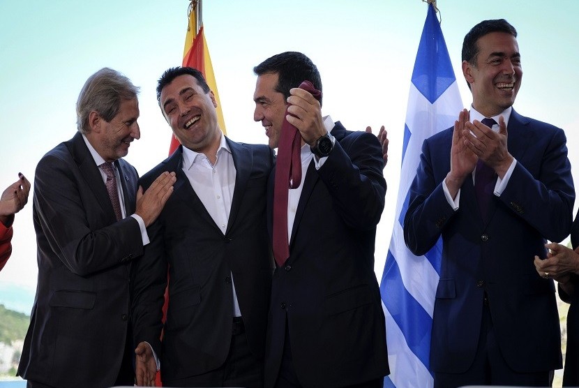 Perdana Menteri Macedonia Zoran Zaev (kedua kiri) secara simbolis menyerahkan dasi kepada Perdana Menteri Yunani Alexis Tsipras (kedua kanan) dihadapan komisioner Uni Eropa dalam penandatanganan antar dua negara di Psarades, Florina, Yunani, Senin (17/6)