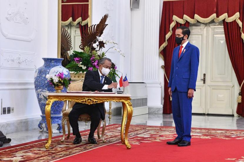 Perdana Menteri  Malaysia Muhyiddin Yassin (kiri) menulis di buku tamu saat bertemu dengan Presiden Indonesia Joko Widodo di Istana Merdeka, Kamis (5/2), di Jakarta, Indonesia. PM Muhyiddin melakukan kunjungan resmi untuk mempererat hubungan bilateral Indonesia dan Malaysia. 