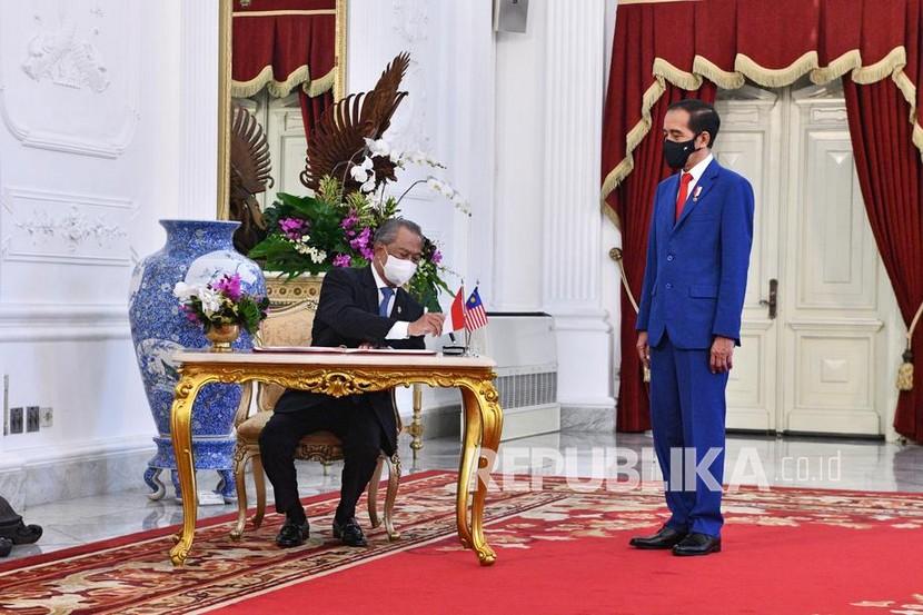 Perdana Menteri  Malaysia Muhyiddin Yassin (kiri) menulis di buku tamu saat bertemu dengan Presiden Indonesia Joko Widodo di Istana Merdeka, Kamis (5/2), di Jakarta, Indonesia. Muhyiddin melawat selama dua hari dalam kunjungan resmi untuk mempererat hubungan bilateral Indonesia dan Malaysia. 