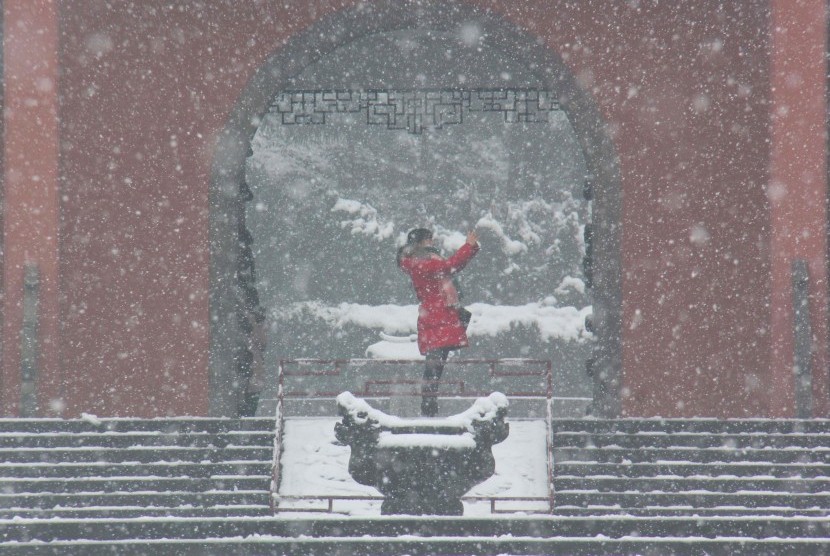 Perempuan berfoto di tengah tebalnya salju yang turun. Mayoritas wilayah China akan mengalami penurunan suhu udara 2-4 derajat Celcius dibanding musim dingin biasa. Ilustrasi.
