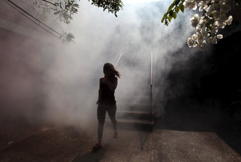 Perempuan berjalan menjauhi tempat tinggalnya yang difumigasi untuk memberantas nyamuk pembawa virus Zika dan penyakit lain yang disebabkan nyamuk di Soyapango, El Salvador, (22/1).