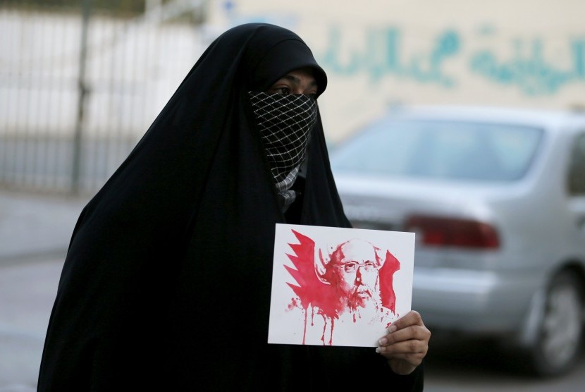 Perempuan berunjuk rasa membawa foto ulama Syiah yang dieksekusi pemerintah Arab Saudi, di Desa Sanabis, Bahrain, Sabtu (2/1).