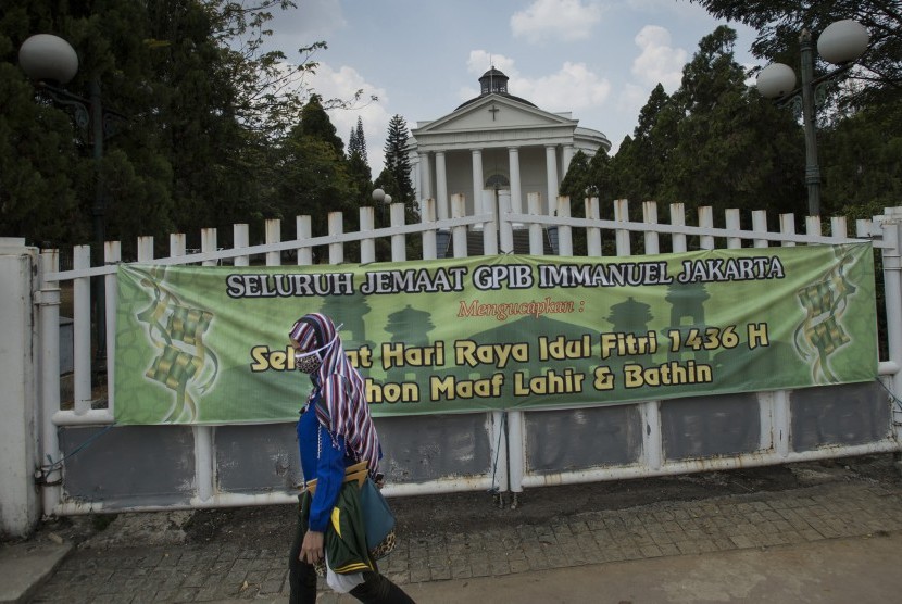 Perempuan melintas di depan spanduk ucapan selamat Idul Fitri di depan Gereja Immanuel, Jakarta, Rabu (22/7).