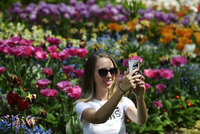 Perempuan mengambil foto dirinya dengan cara swafoto alias selfie.