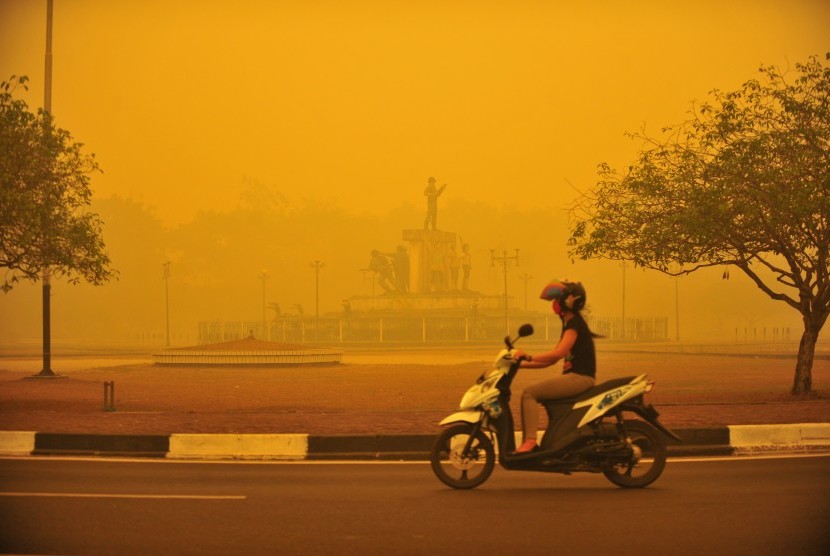 Perempuan mengendarai motor melewati kabut asap di Palangkaraya (23/10).