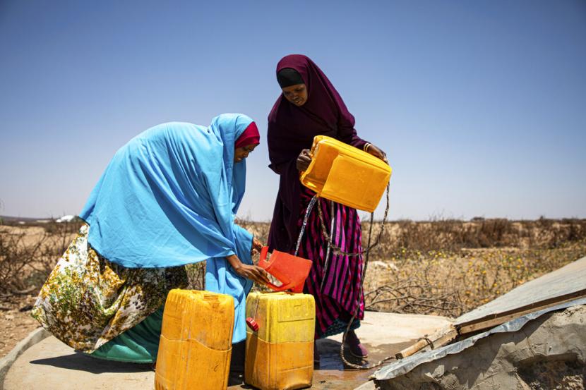 Perempuan mengisi wadah plastik dengan air di komunitas Xidhinta di Somaliland, wilayah semi-otonom Somalia, pada 14 Maret 2022. Diperkirakan 13 juta orang menghadapi kelaparan parah di Tanduk Afrika sebagai akibat dari kondisi kekeringan yang terus-menerus, menurut PBB.