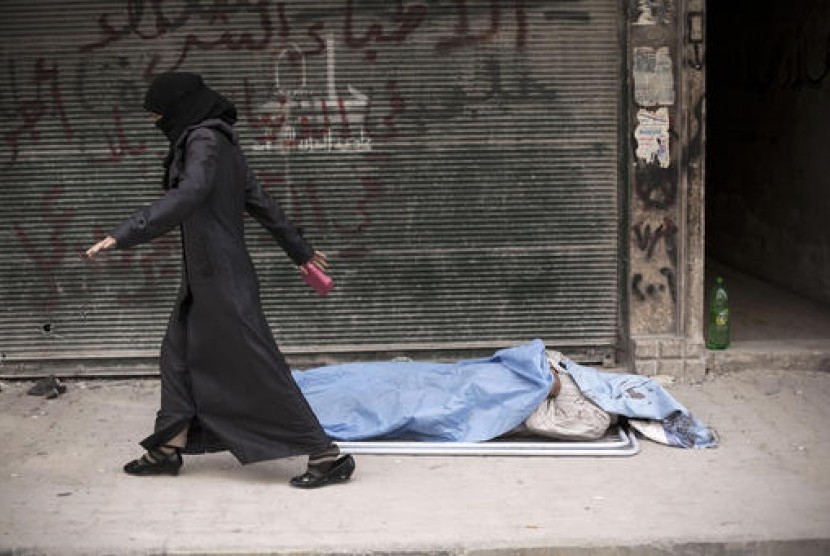 Perempuan Suriah berjalan melewati sebuah jasad yang tergeletak di tepi jalan Aleppo.