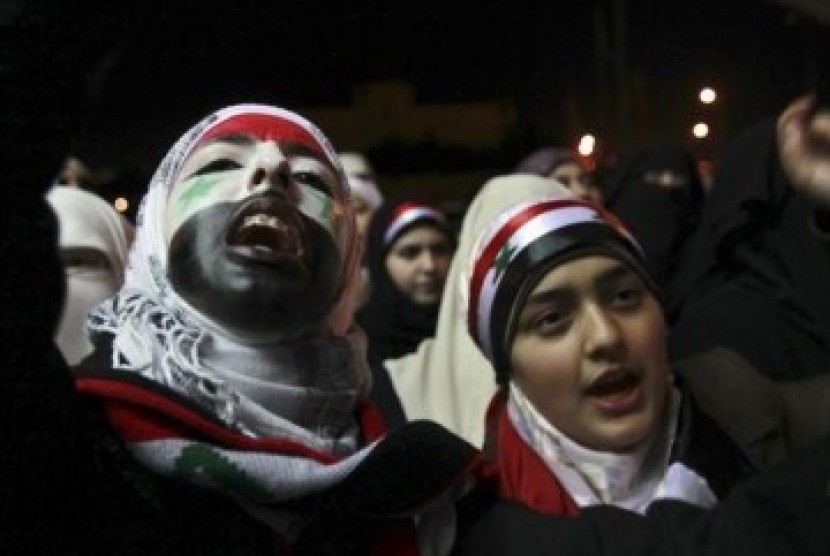 Perempuan Suriah mengecat wajah mereka dengan warna bendera Suriah dan meneriakkan slogan anti-pemerintahan Presiden Suriah Bashar Al-Asad. 