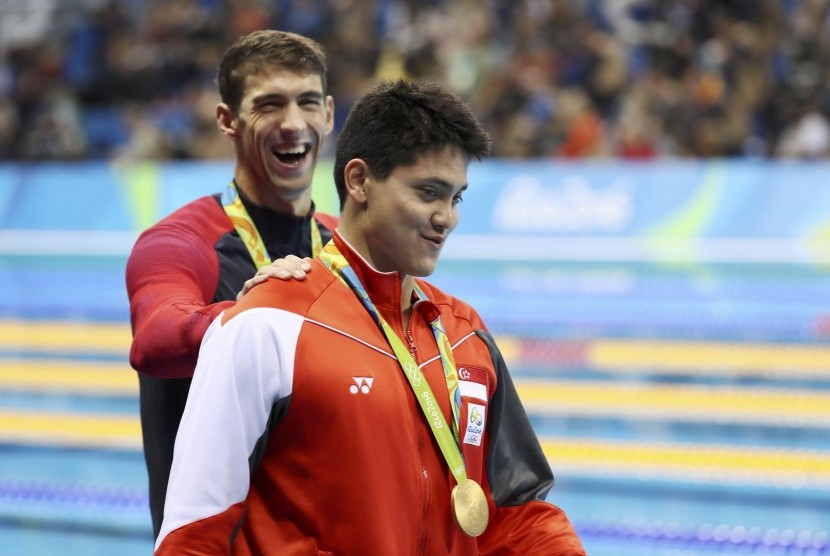 Perenang AS Michael Phelps memberi selamat perenang Singapura Joseph Schooling usai penganugrahan medali di Olimpiade Rio. Sabtu (13/8), Schooling mengalahkan Phelps di kategori renang gaya kupu-kupu.