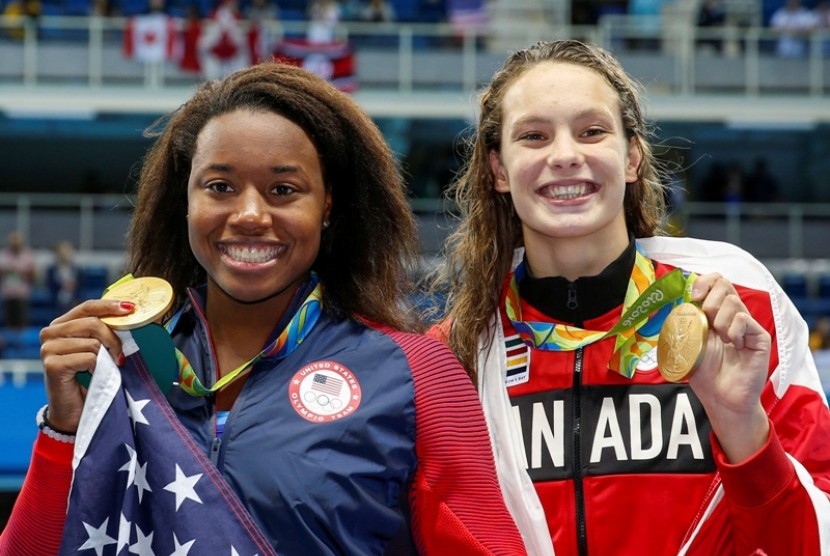 Perenang AS Simone Manuel (kiri) dan perenang Kanada Penny Oleksiak sama-sama meraih medali emas 100 meter putri di Olimpiade Rio de Janeiro.