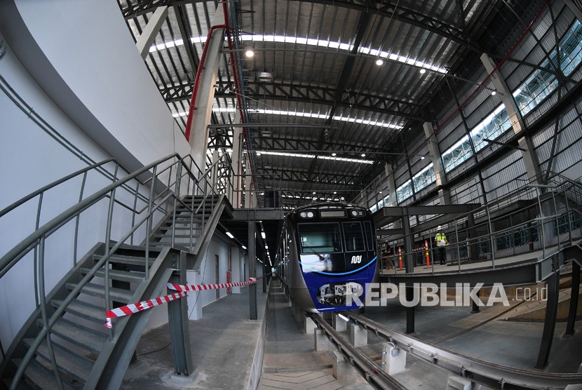 Perkerja melintas di dekat kepala kereta MRT di Depo MRT Lebak Bulus, Jakarta, Kamis (12/4).
