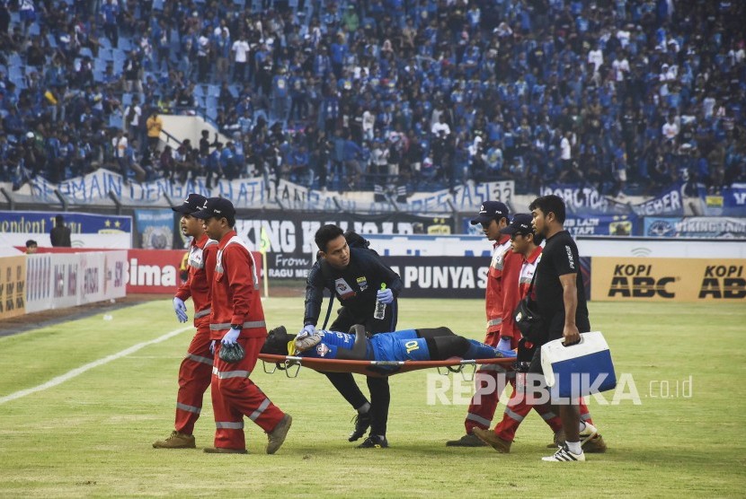 Persib Bandung Imbang Melawan Madura United. Penyerang Persib Bandung Ezechiel Ndouasel ditandu keluar lapangan pada pertandingan Sepak Bola Liga 1 2019 di Stadion Si Jalak Harupat, Kabupaten Bandung, Ahad (23/6). 