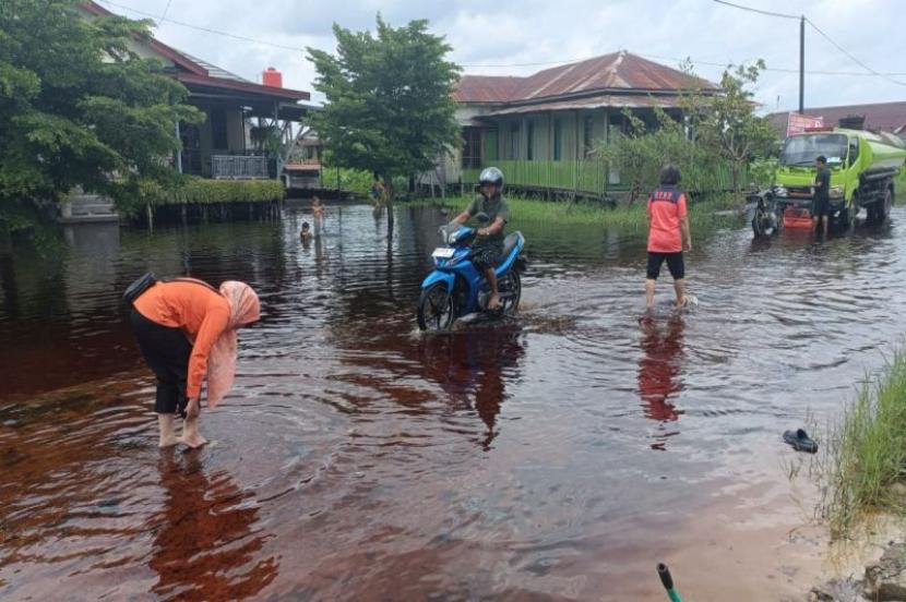 Personel BPBD Kota Palangka Raya melakukan pemantauan di salah satu permukiman warga yang bagian jalannya terendam banjir akibat luapan sungai di sekitarnya, Selasa (23/1/2024).