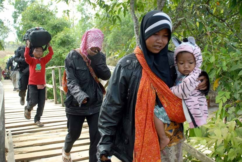   Personel Brimob mengawal sejumlah perempuan dan anak-anak, ketika berlangsungnya evakuasi dari tempat persembunyian mereka, di Desa Karanggayam dan Desa Bluuran, Sampang, Jatim, Senin (27/8). (Saiful Bahri/Antara)