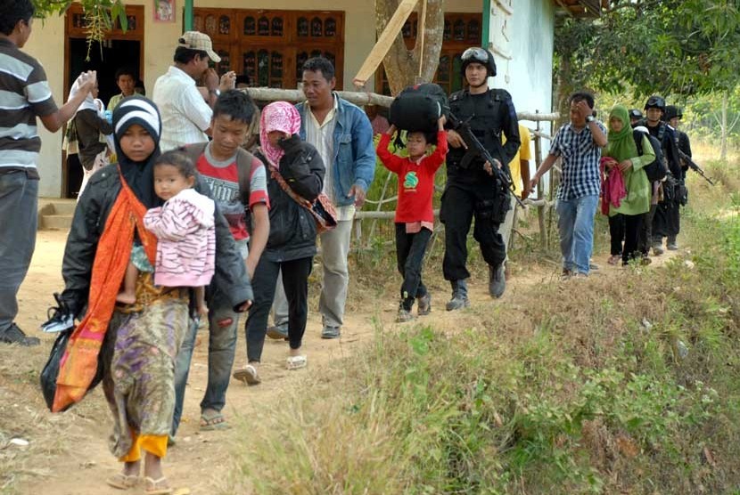   Personel Brimob mengawal sejumlah perempuan dan anak-anak, ketika berlangsungnya evakuasi dari tempat persembunyian mereka, di Desa Karanggayam dan Desa Bluuran, Sampang, Jatim, Senin (27/8). (Saiful Bahri/Antara)