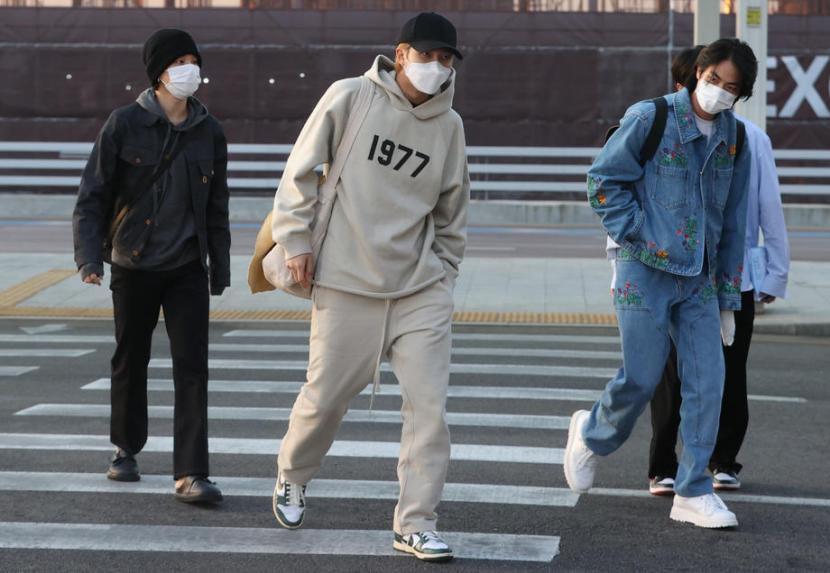 Personel BTS (kiri-kanan) Jimin, RM, dan Jin tiba di Incheon International Airport, Korea Selatan untuk terbang ke Las Vegas, AS  pada 28 Maret 2022. Tangan Jin tampak dibalut gips pasca operasi telunjuk kiri.