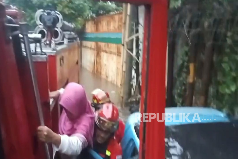 Personel Damkat Kota Cimahi Mengevakuasi Penumpang yang Terjebak dalam Mobil Saat Banjir Menerjang Jalan Mahar Martanegara, Kota Cimahi pada Sabtu (15/3) Sore.