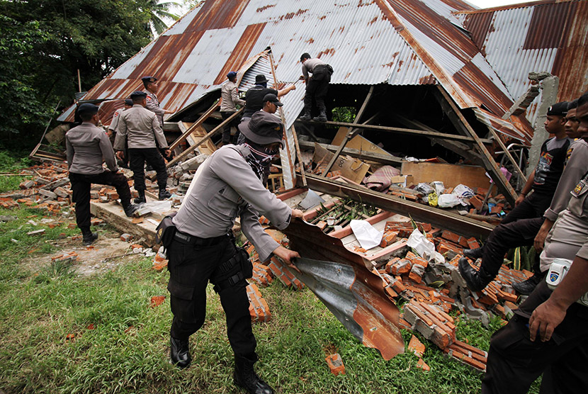 Personel gabungan TNI-Polri membersihkan puing bangunan pasar yang roboh akibat gempa bumi 6,5 SR di Pidie Jaya, Aceh, Sabtu (10/12).