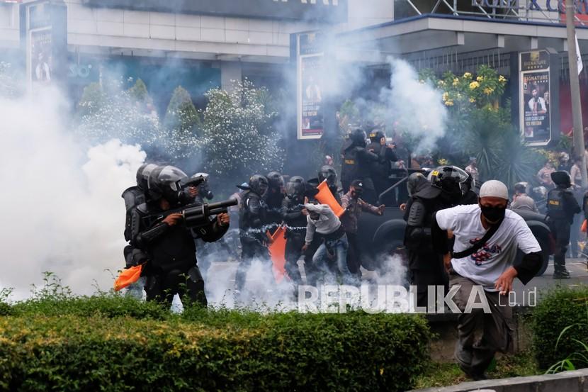 Personel kepolisian menembakkan gas air mata ke arah pengunjuk rasa saat demonstrasi menentang Omnibus Law Undang-Undang (UU) Cipta Kerja di Kota Magelang, Jawa Tengah, Jumat (9/10/2020). Unjuk rasa tersebut berakhir ricuh dan mengakibatkan sejumlah fasilitas umum rusak.