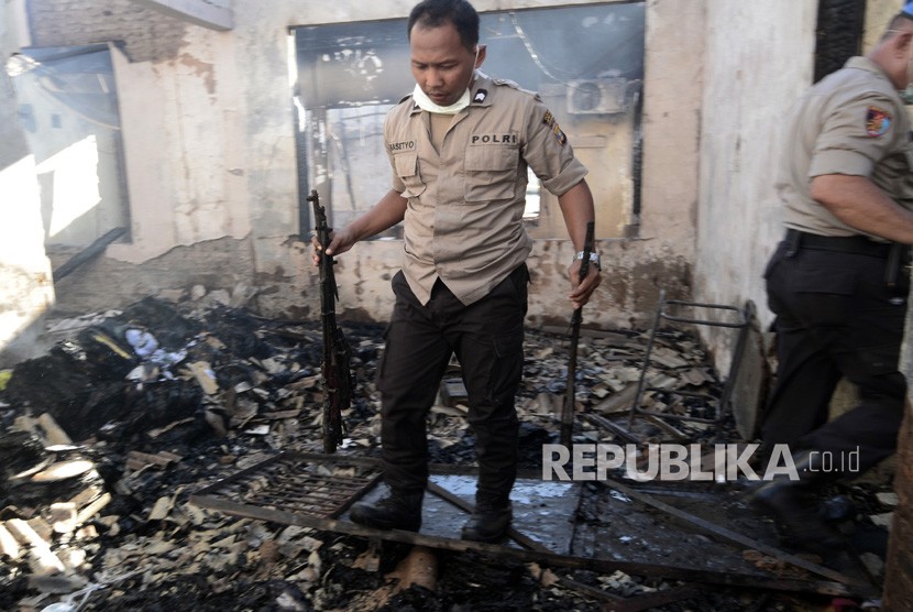 Personel kepolisian mengumpulkan senjata api yang terbakar di gudang senjata milik Polres Lampung Selatan, Lampung, Kamis (2/5/2019). 