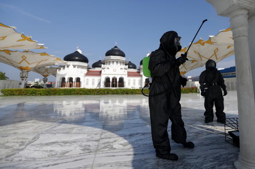 Personel Polda Aceh melakukan penyemprotan cairan disinfektan di Masjid Raya Baiturrahman, Banda Aceh, demi mencegah penyebaran corona.