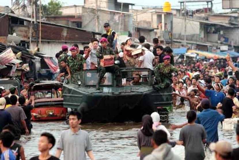 Personel Marinir TNI AL menggunakan kendaraan tempur Amfibi untuk mengevakuasi korban banjir dan mendistribusikan paket bantuan kepada korban banjir di Kawasan Muara Baru, Jakarta, Ahad (20/1).