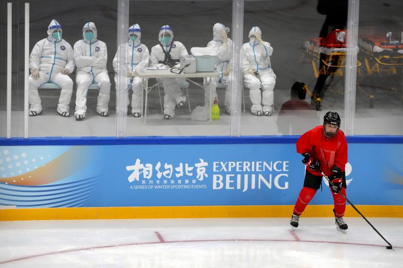 Personel medis dengan pakaian pelindung menyaksikan tim hoki China Ice Sports College berlatih di atas es selama Kegiatan Tes Domestik Hoki Es Beijing, acara uji untuk Olimpiade Musim Dingin Beijing 2022, di Stadion Indoor Nasional di Beijing, Rabu, 11 November. 10, 2021.