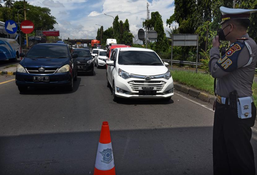Personel Polantas menerapkan sistem buka tutup untuk kendaraan yang keluar dari jalan Tol Tangerang-Merak di Jalan Cikuasa menuju Pelabuhan Merak, Kota Cilegon, Provinsi Banten, Rabu (27/4/2022).
