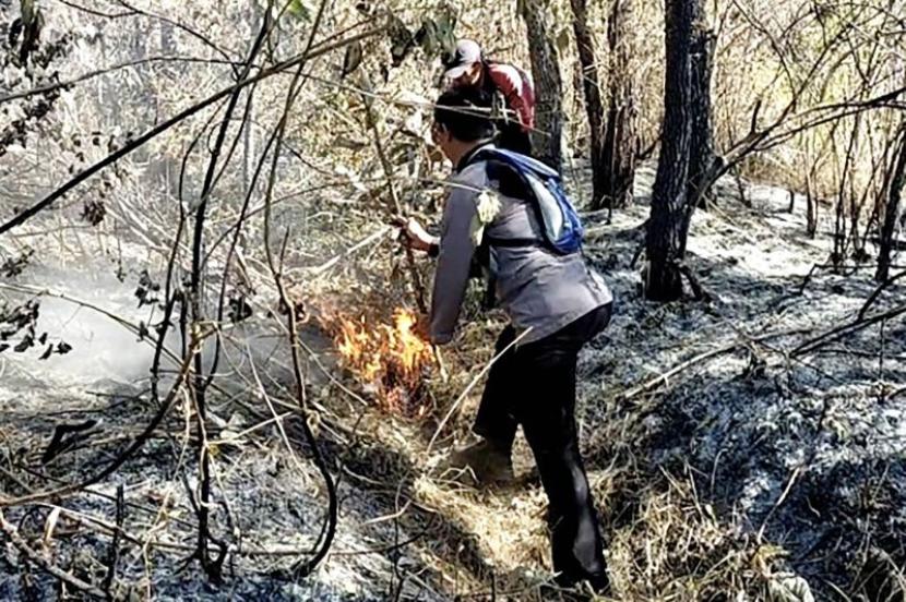 Personel Polres Malang berusaha memadamkan api yang membakar salah satu area di kawasan Gunung Arjuno, di wilayah Kecamatan Singosari, Kabupaten Malang, Jawa Timur, Ahad (27/8/2023).