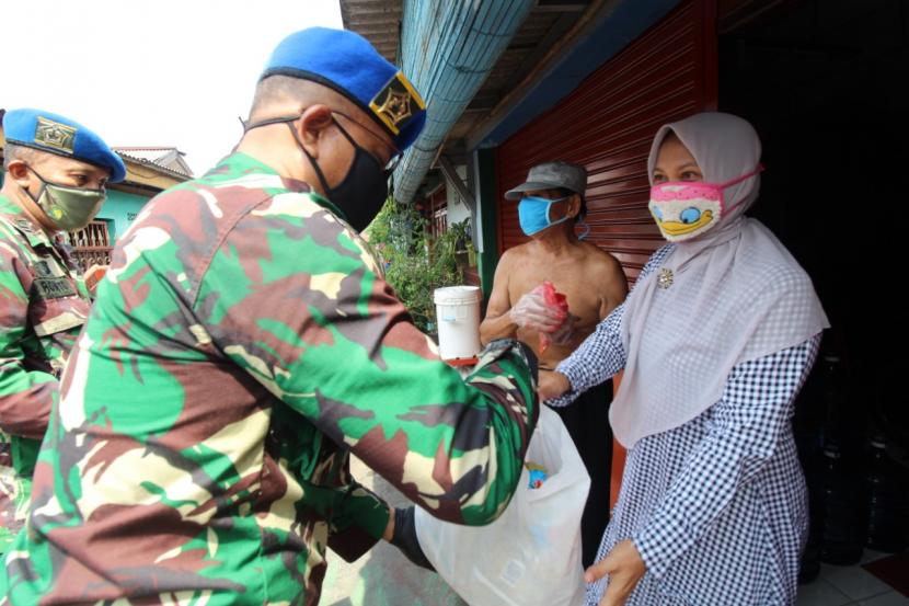 Personel Pusat Polisi Militer Angkatan Darat (Puspomad) dengan memakai masker membagikan paket sembako ke masyarakat di tengah pandemi Covid-19