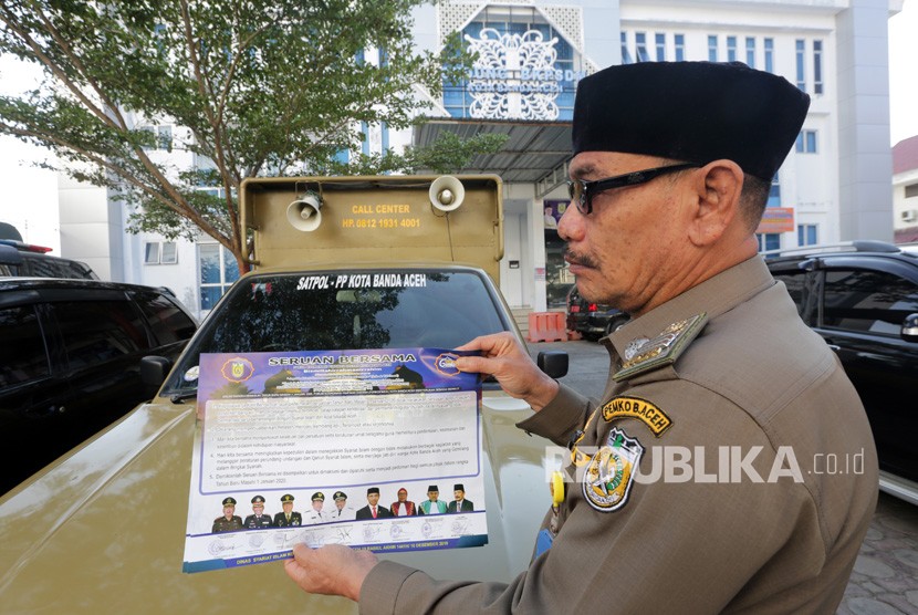 Personel Satpol PP dan Wilayatul Hisbah (Polisi Syariat Islam) memperlihatkan seruan bersama larangan perayaan pergantian tahun mesehi dari 2019 ke 2020 di Banda Aceh, Aceh, Jumat (27/12/2019). 